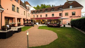 A hotel courtyard with outdoor seating, a covered area, and a well-maintained lawn. - Hotel Hoffmeister (Prague)