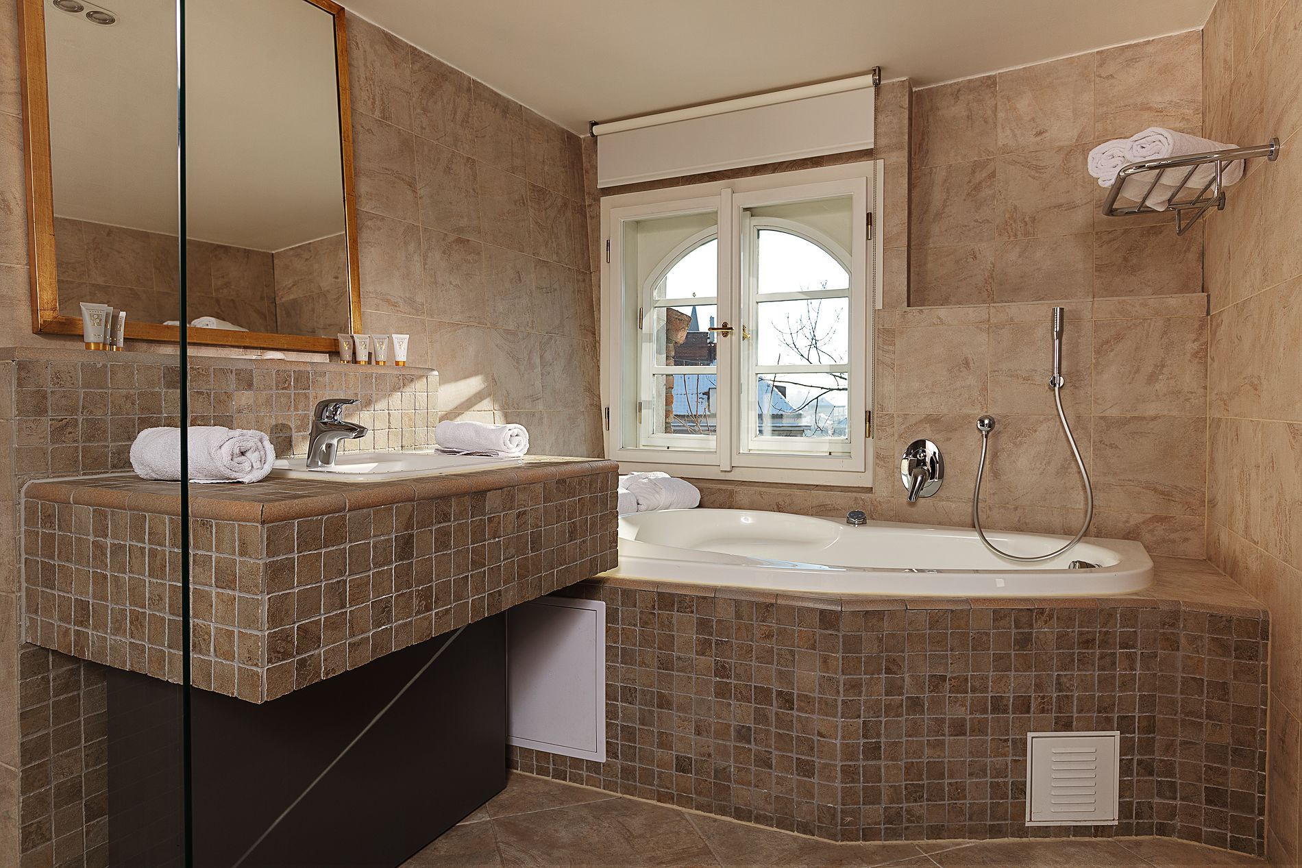 Une salle de bain moderne dotée d’une grande baignoire, d’un meuble-lavabo avec un miroir et d’une fenêtre offrant une vue sur l’extérieur.