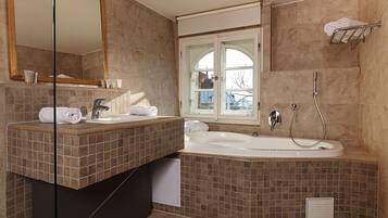 A modern bathroom with a large bathtub, a vanity with a mirror, and a window providing a view of the outside.