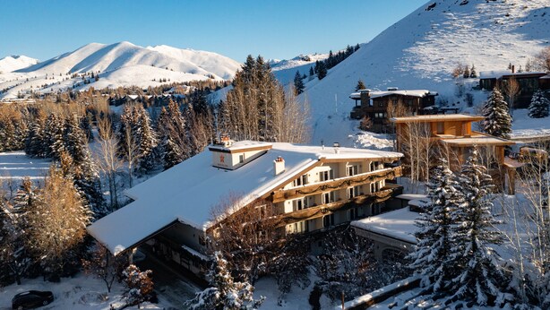 A snow-covered lodge with multiple buildings, surrounded by snow-covered trees and mountains in the background. - Knob Hill Inn (Ketchum)