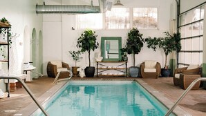 An indoor swimming pool with clear water, surrounded by lounge chairs and potted plants. - Knob Hill Inn (Ketchum)