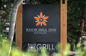 A sign for Knob Hill Inn in Sun Valley with a logo and mentions a Grill.