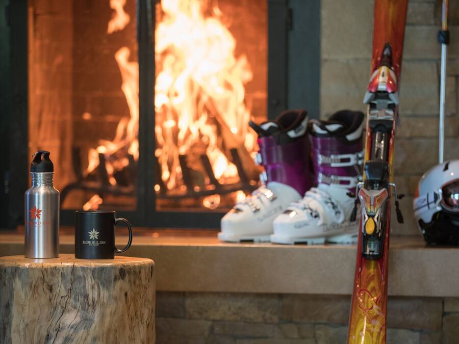 A fireplace with skis and snowboards leaning against the wall.