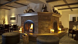 A cozy interior with a stone fireplace, seating area, and a dining setup. - Knob Hill Inn (Ketchum)