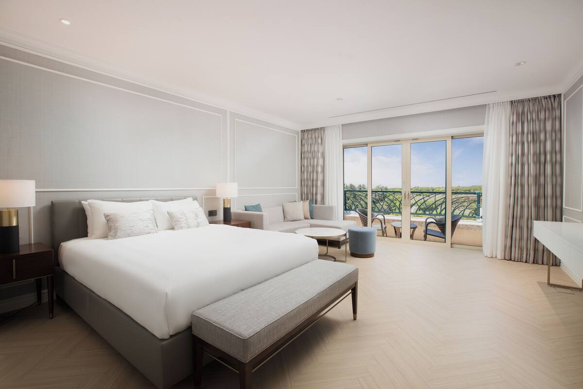 Une chambre d’hôtel moderne dotée d’un grand lit, d’un coin salon et d’un balcon avec vue.