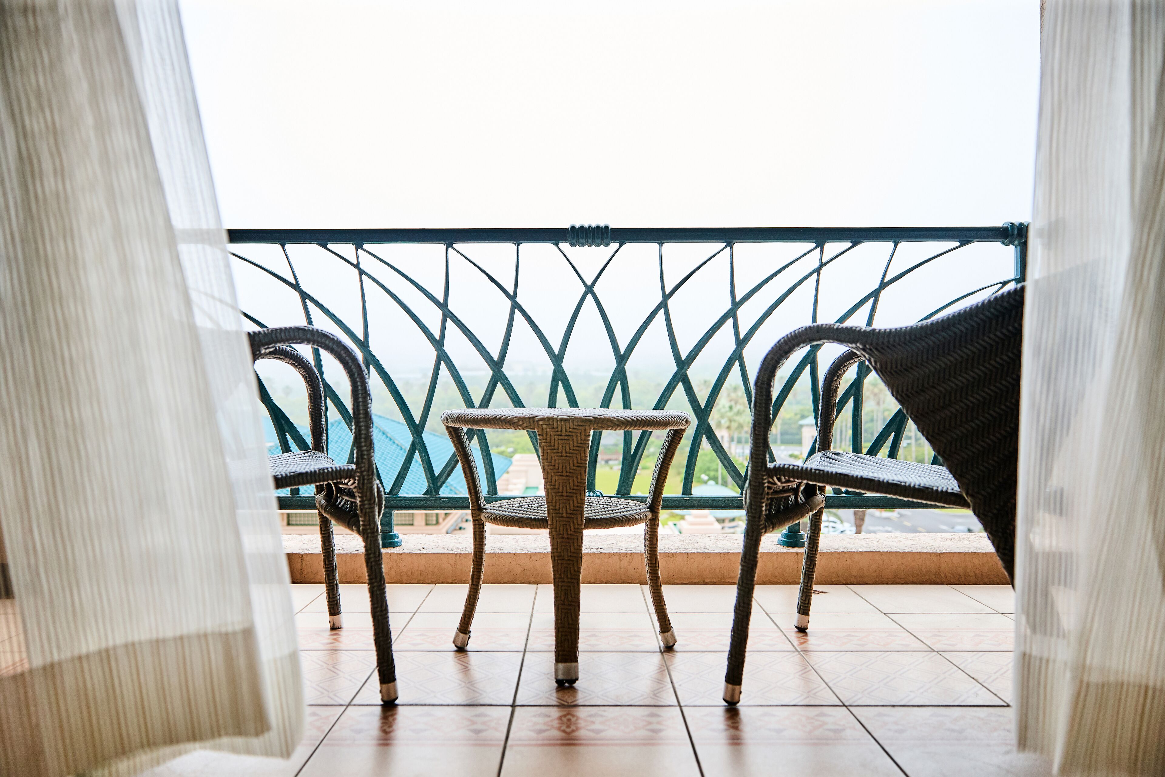 Ein Balkon mit Korbstühlen und einem kleinen Tisch, mit Blick auf eine reizvolle Aussicht.
