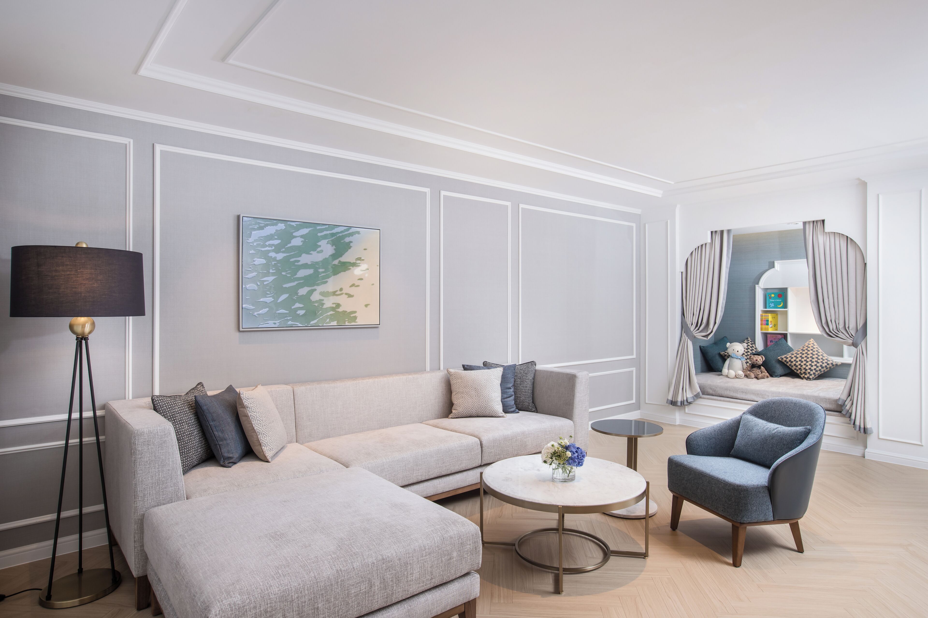 Un salon moderne avec un canapé d’angle, une table basse ronde et un fauteuil bleu.