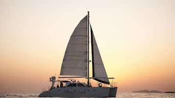 A sailboat named 'Shanghai La II' on calm waters during sunset.