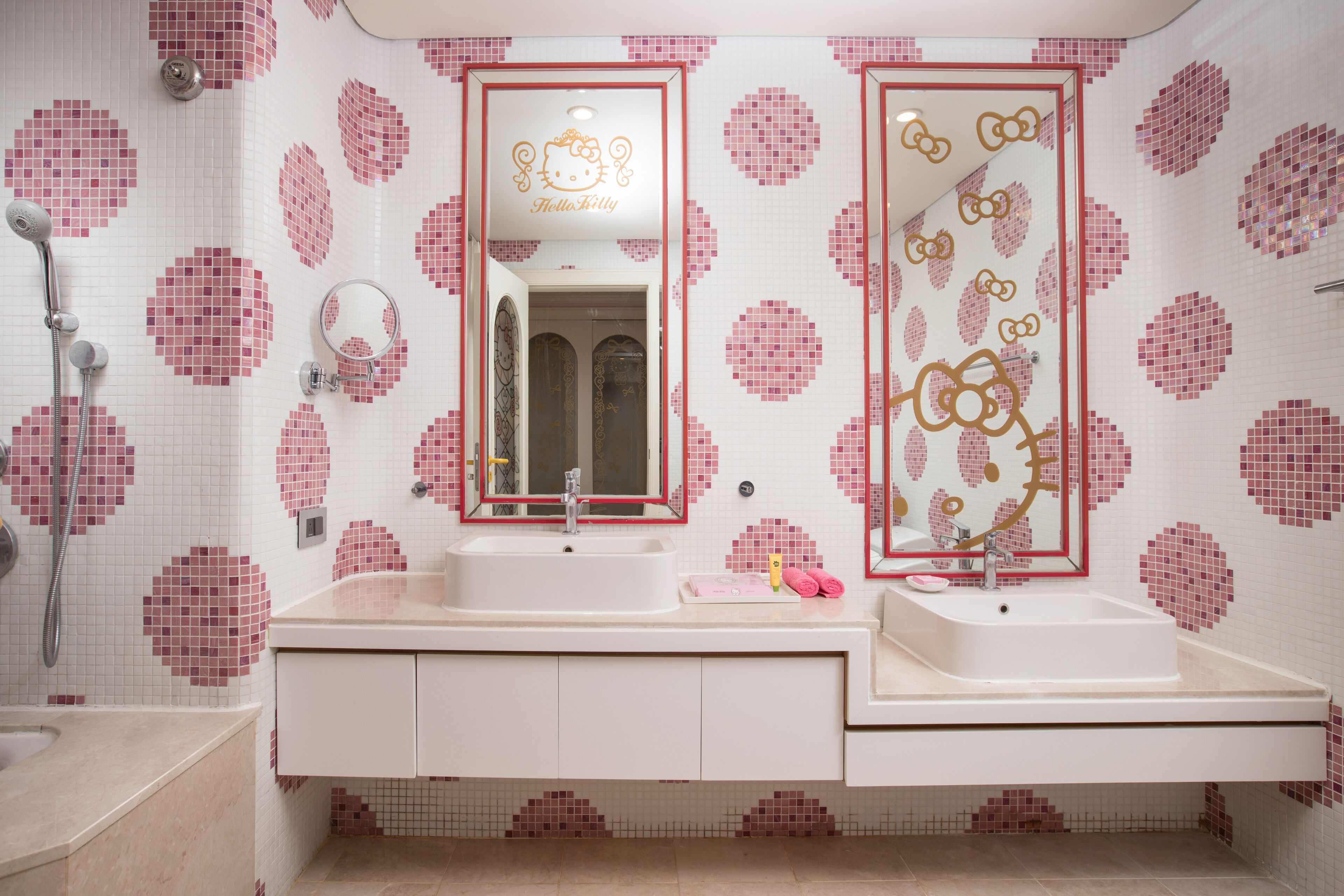 A bathroom with two sinks, a shower, and a mirror with Hello Kitty decorations.