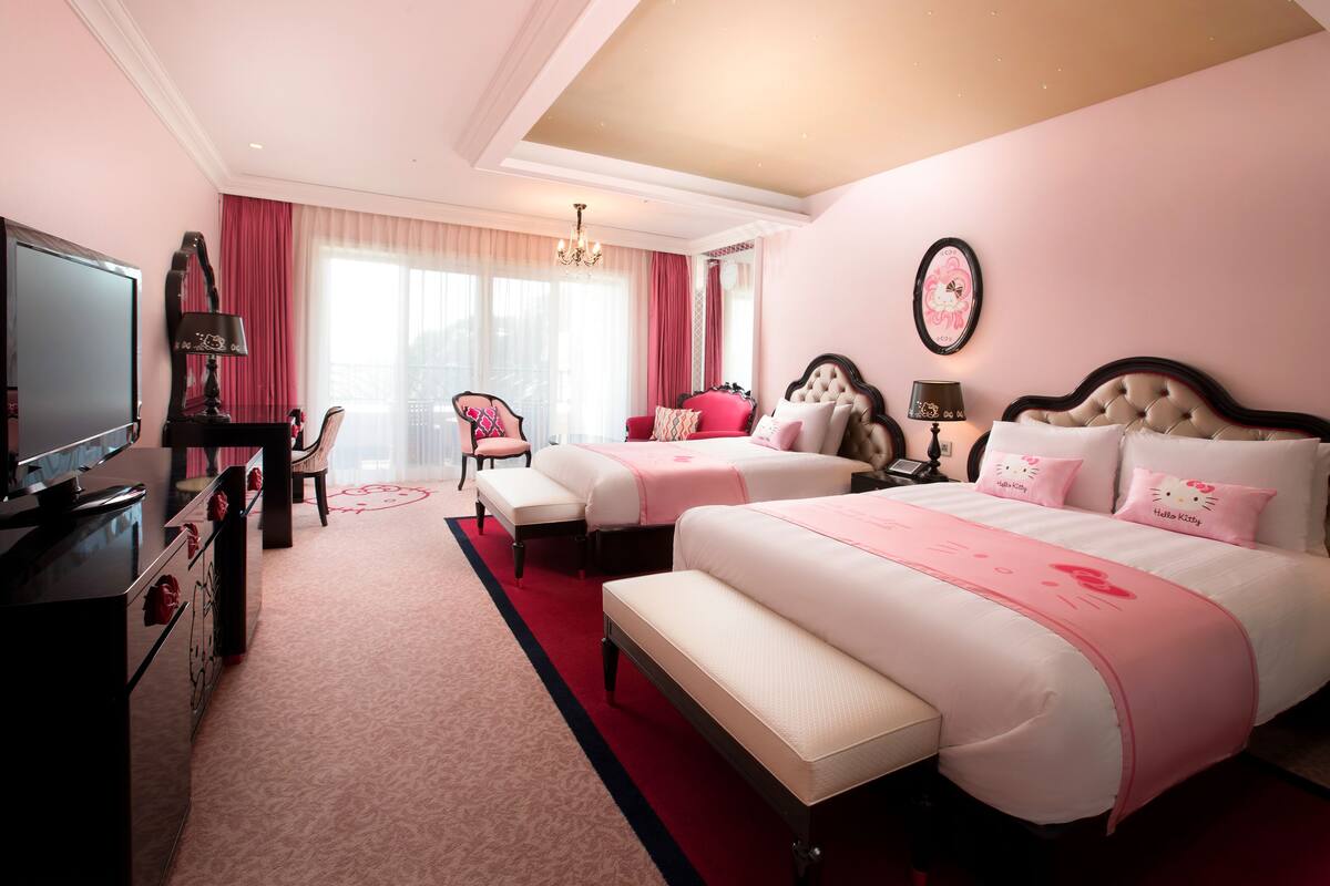 Une chambre d’hôtel avec deux lits, une télévision, un bureau et une chaise.