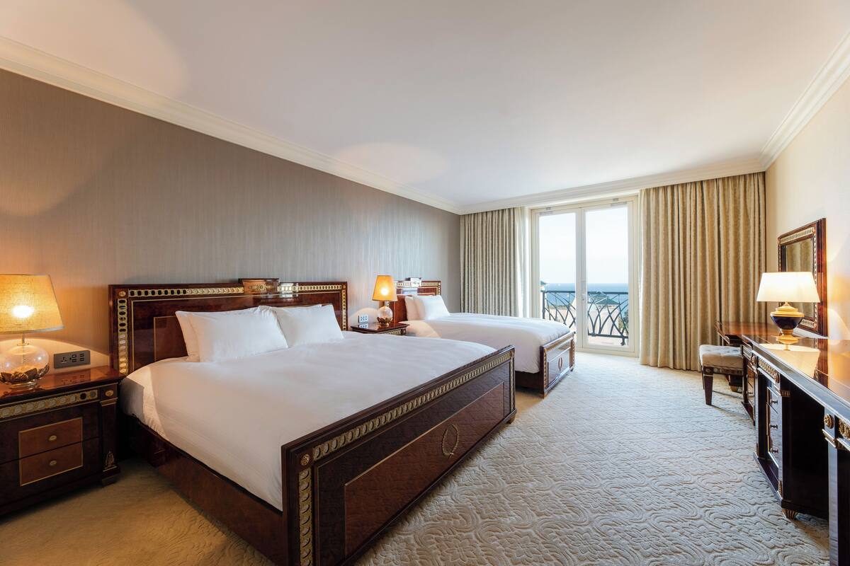 Une chambre d’hôtel avec deux lits, un bureau et une vue sur l’extérieur.