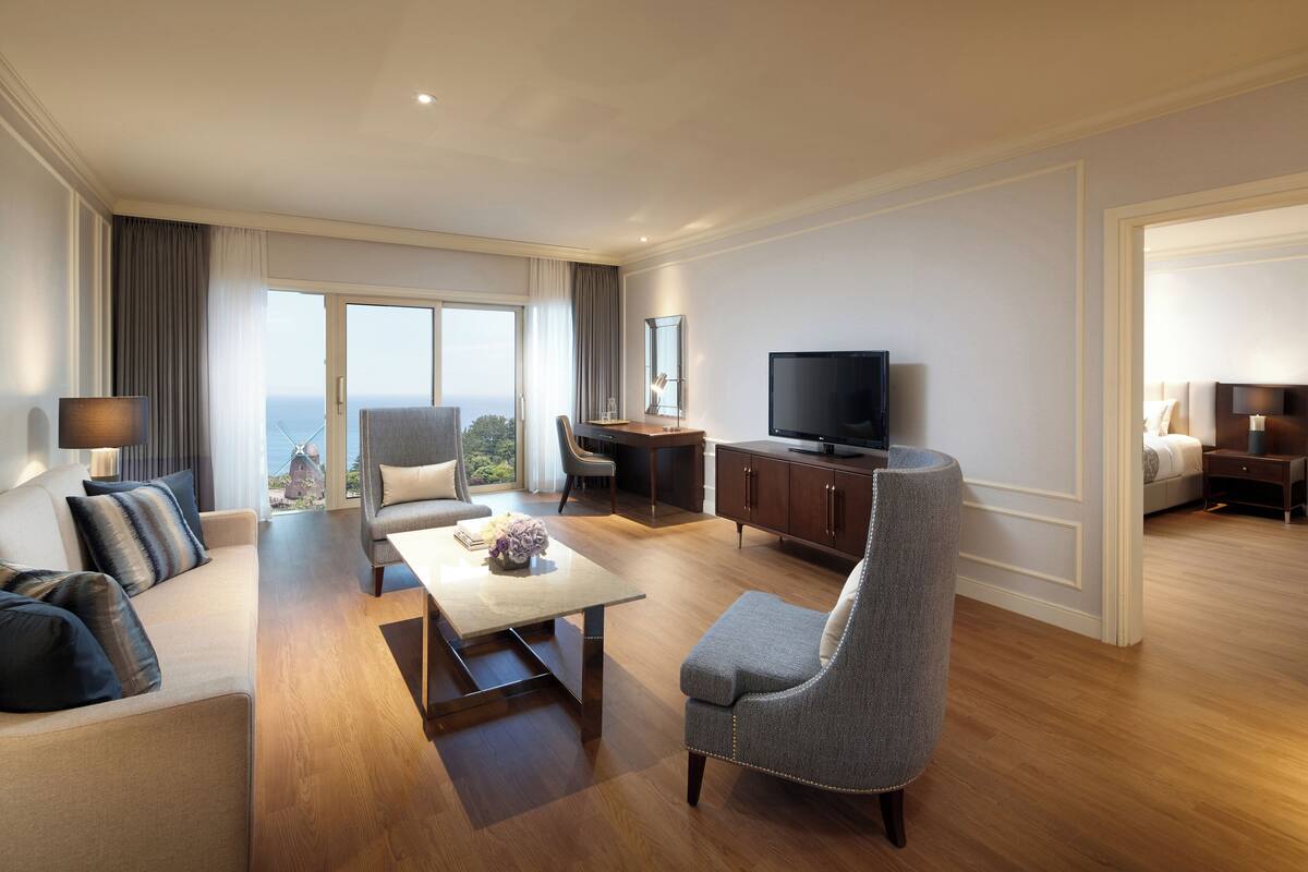 Une chambre d’hôtel moderne dotée d’un espace salon, d’une table à manger, d’une télévision et offrant une vue sur la ville.