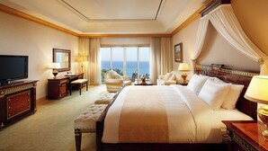 Une chambre d’hôtel spacieuse, dotée d’un grand lit, d’une télévision, d’un bureau avec une chaise et offrant une vue sur la mer.