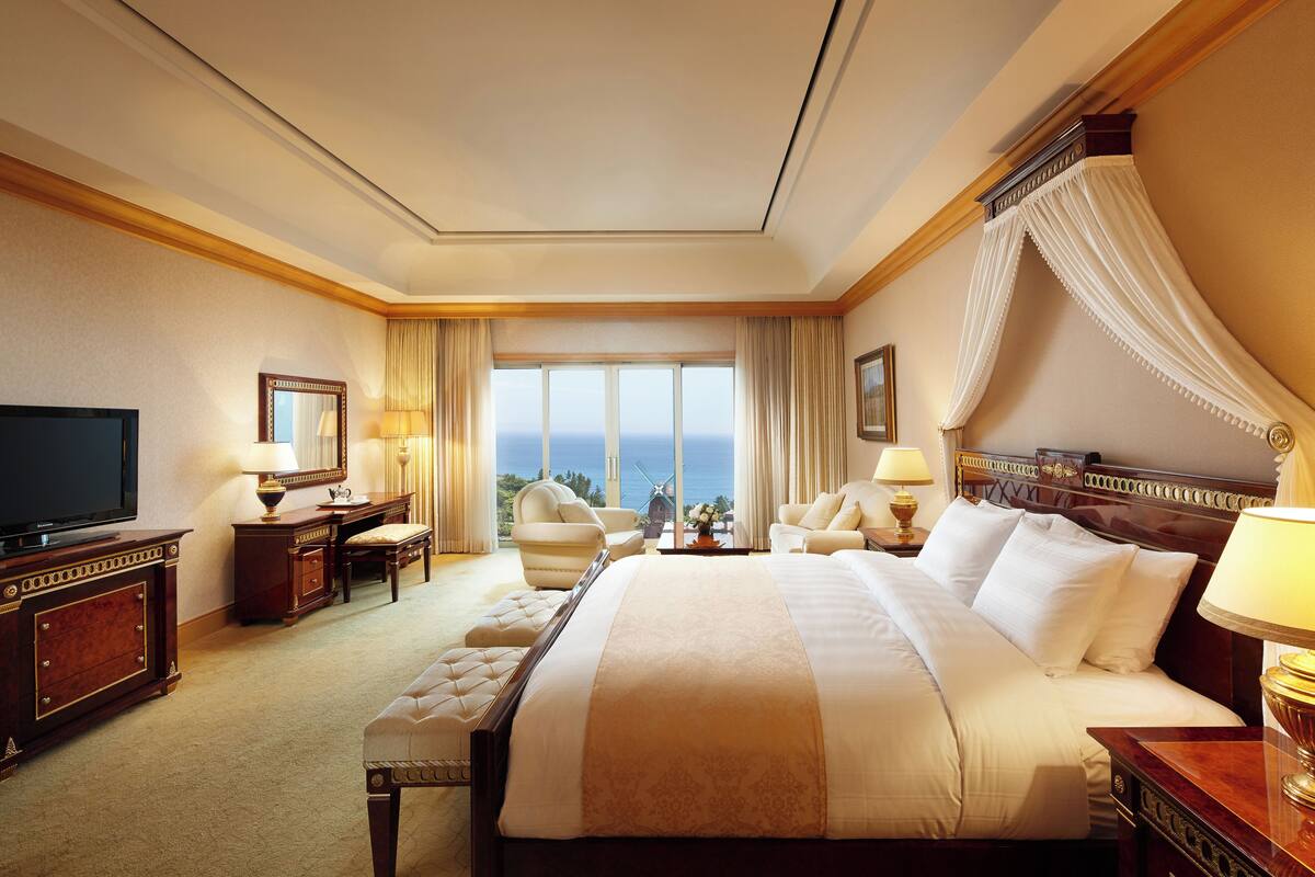 Une chambre d’hôtel spacieuse, dotée d’un grand lit, d’une télévision, d’un bureau avec une chaise et offrant une vue sur la mer.