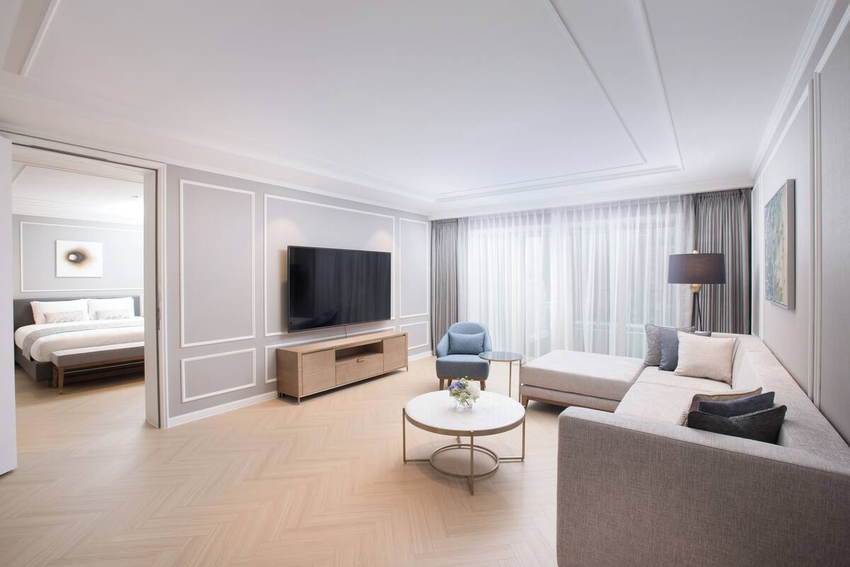 Une chambre d’hôtel moderne équipée d’un lit, d’un canapé, d’une télévision, d’une table basse et d’une lampe.