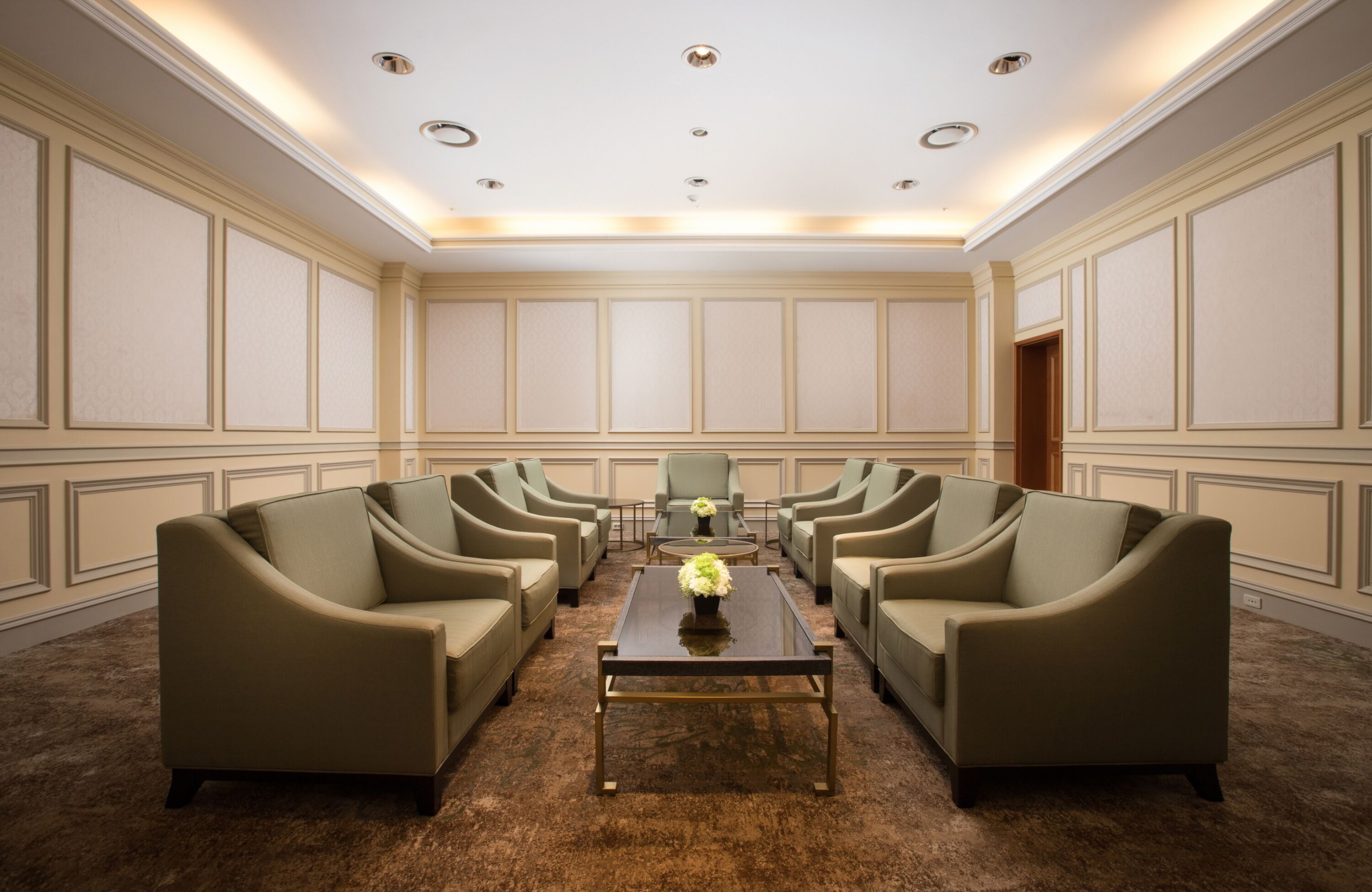 A conference room with six sofas arranged in a U-shape around a central table, with a door on the far wall.
