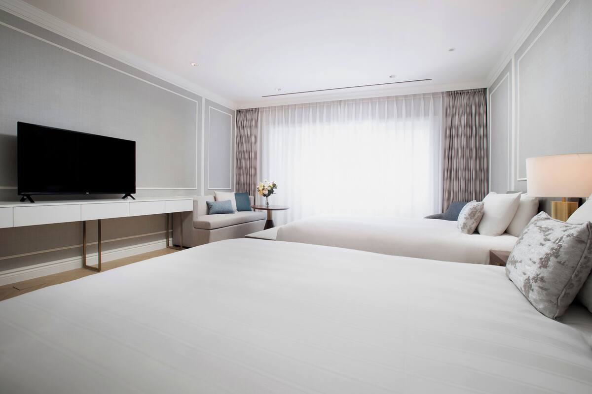 Une chambre d’hôtel moderne avec un grand lit, une télévision, un canapé et une petite table avec une lampe.