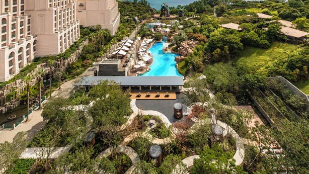 Un resort con una piscina amplia, molinos de viento y abundante vegetación.