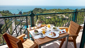 Una mesa lista para el desayuno, con vista al océano y a molinos.