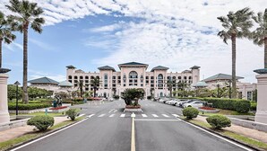 Un hotel grande con fachada simétrica, varios pisos y un patio central con palmeras.