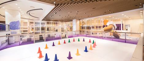 A modern indoor space with a circular arrangement of colorful cones, wooden slatted ceiling, and glass partitions.