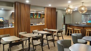 A restaurant with multiple tables and chairs, a counter with a beverage dispenser, and decorative wooden panels. - Springhill Suites By Marriott Atlanta Six Flags (Lithia Springs)