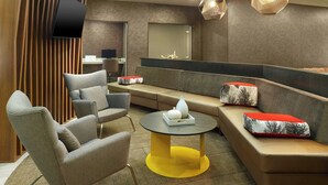 A modern lounge area with a sofa, armchairs, and a small round table. - Springhill Suites By Marriott Atlanta Six Flags (Lithia Springs)