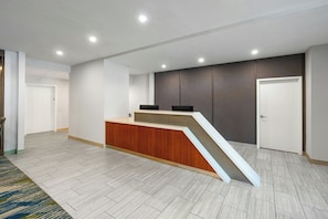 A reception area with a wooden counter, a ramp, and a dark wall panel. - SpringHill Suites by Marriott Atlanta Kennesaw (Kennesaw)