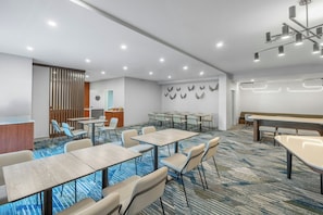 A modern conference room with tables, chairs, a reception desk, and a decorative wall. - SpringHill Suites by Marriott Atlanta Kennesaw (Kennesaw)