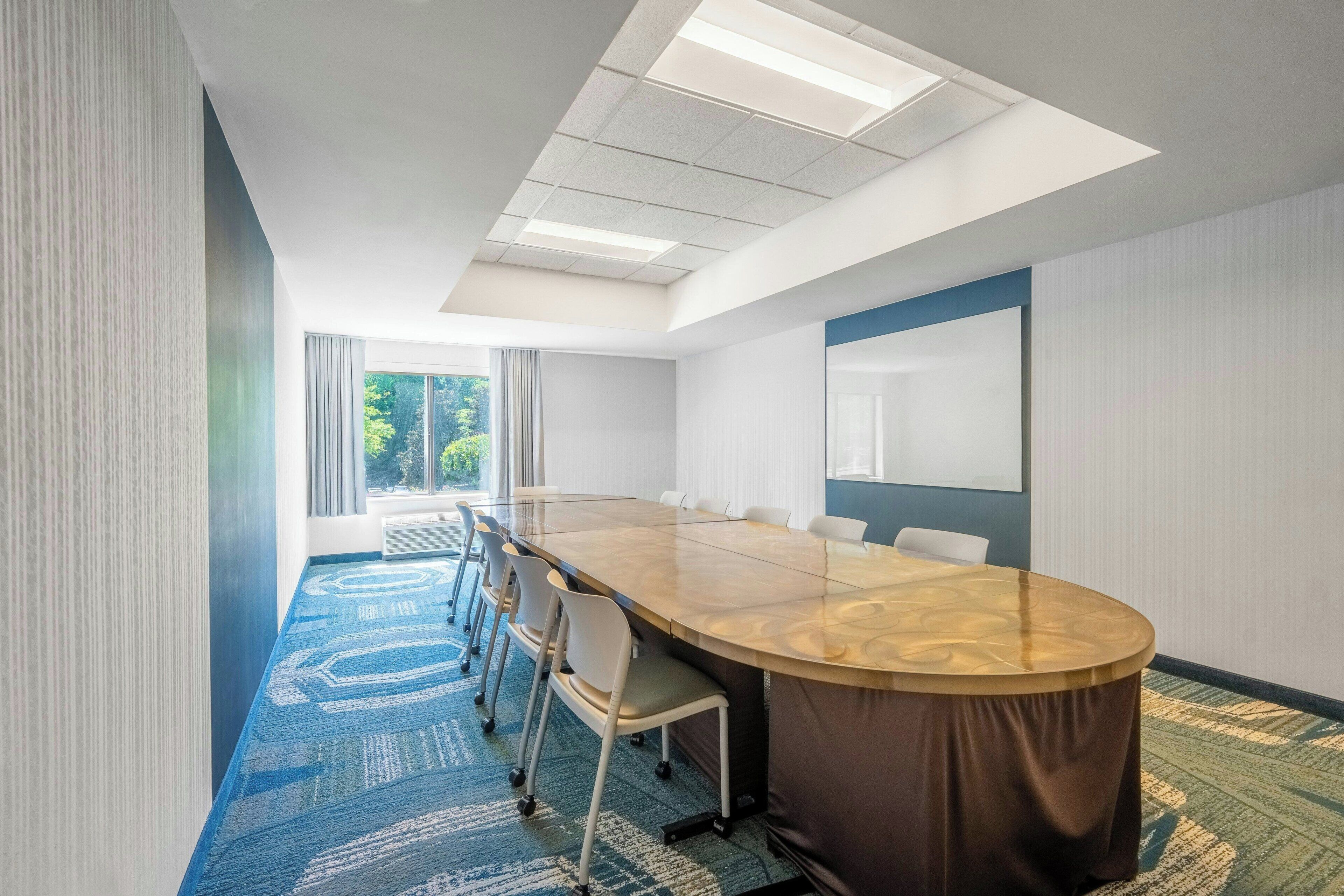 Une salle de conférence dotée d’une longue table, de chaises, d’une grande fenêtre et d’un plafond agrémenté de lucarnes.