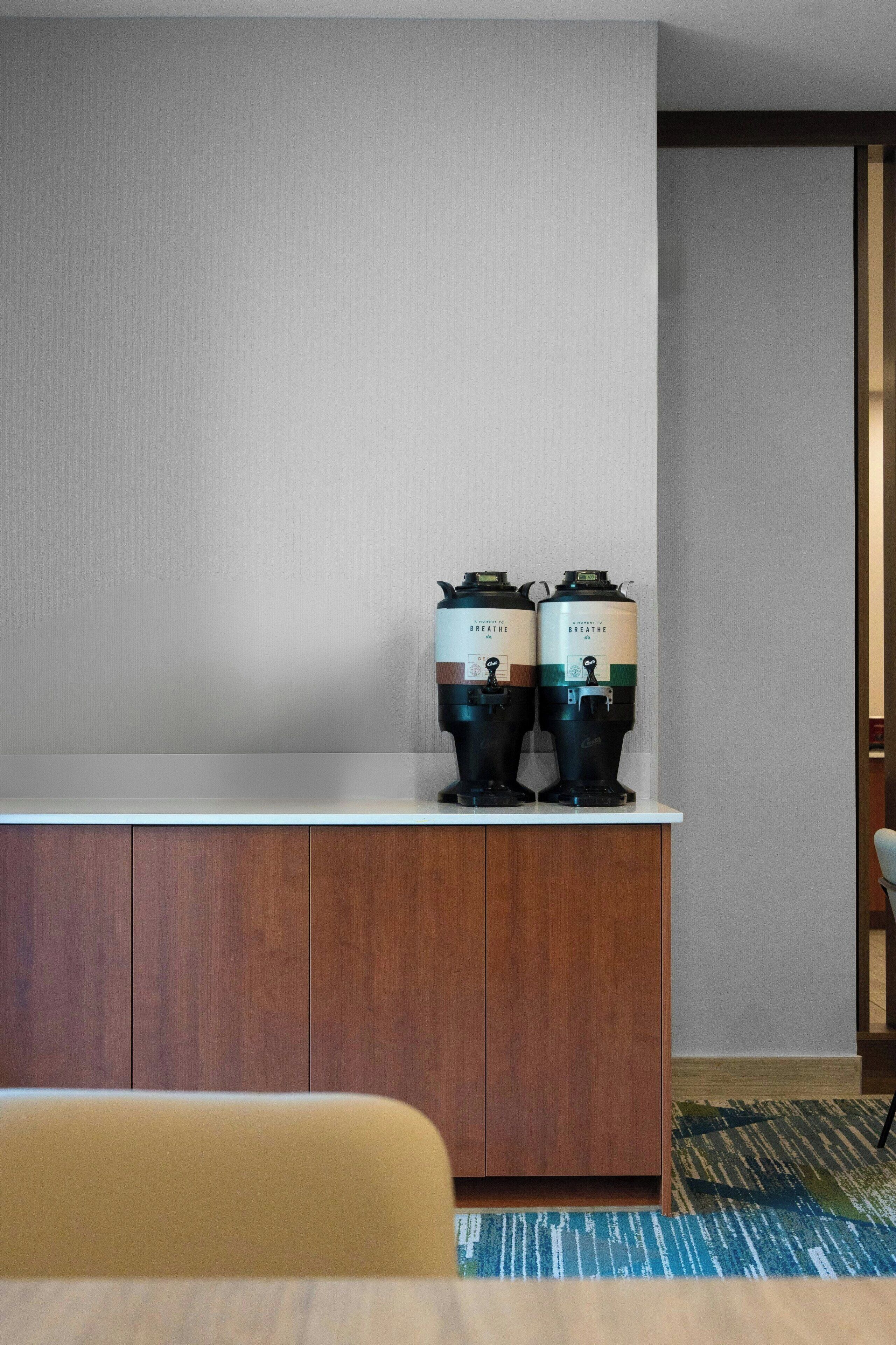 Une chambre moderne avec un meuble en bois, deux purificateurs d’air portant l’inscription « Breathe », et un tapis à motifs.