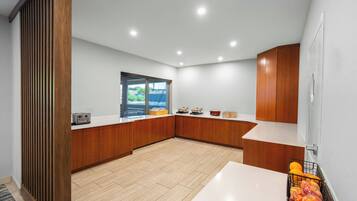 Una cocina moderna con armarios de madera, encimera blanca y un ventanal grande.