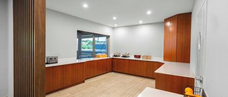 Una cocina moderna con armarios de madera, encimera blanca y un ventanal grande.