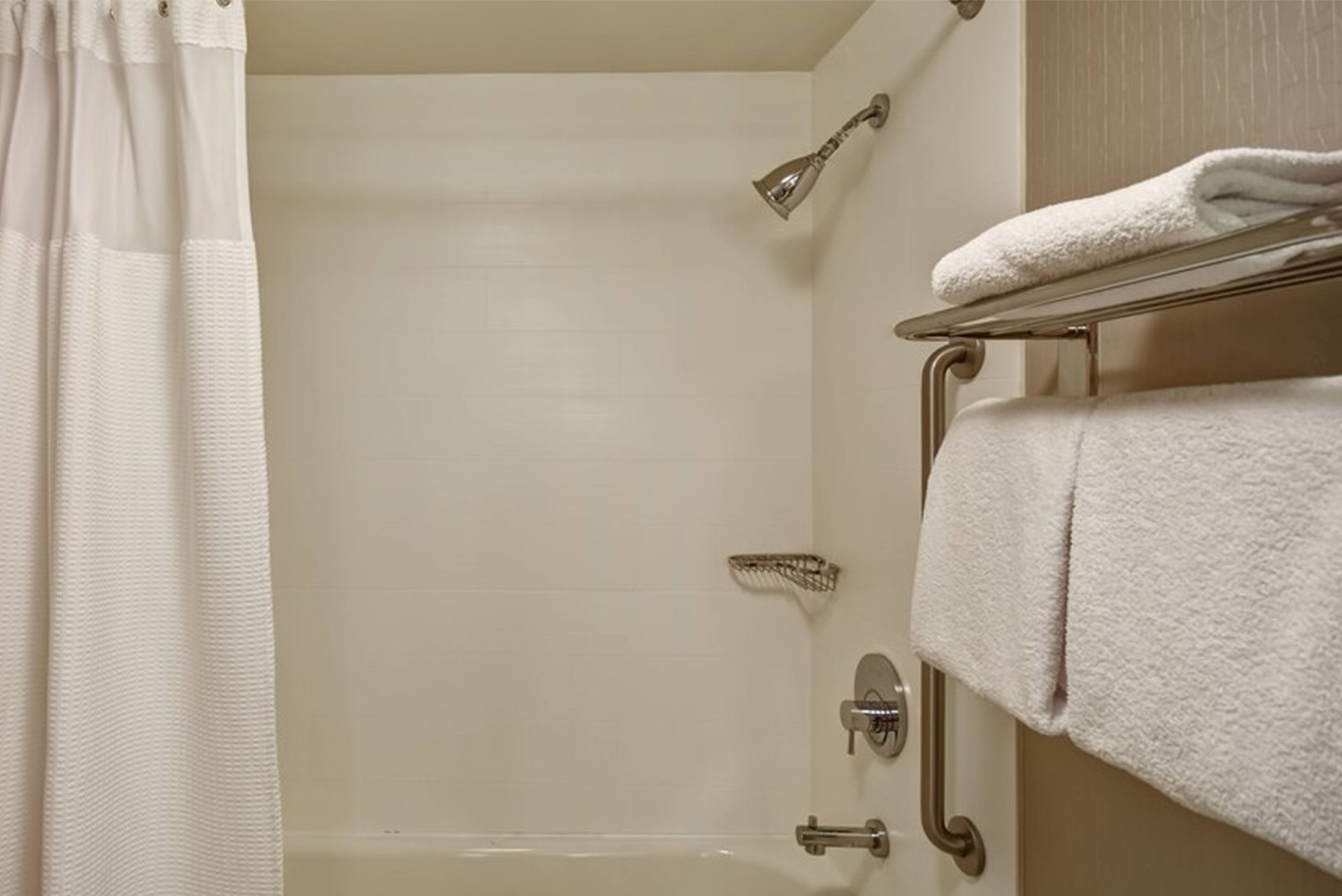 Un bagno con doccia, asciugamano e maniglione.