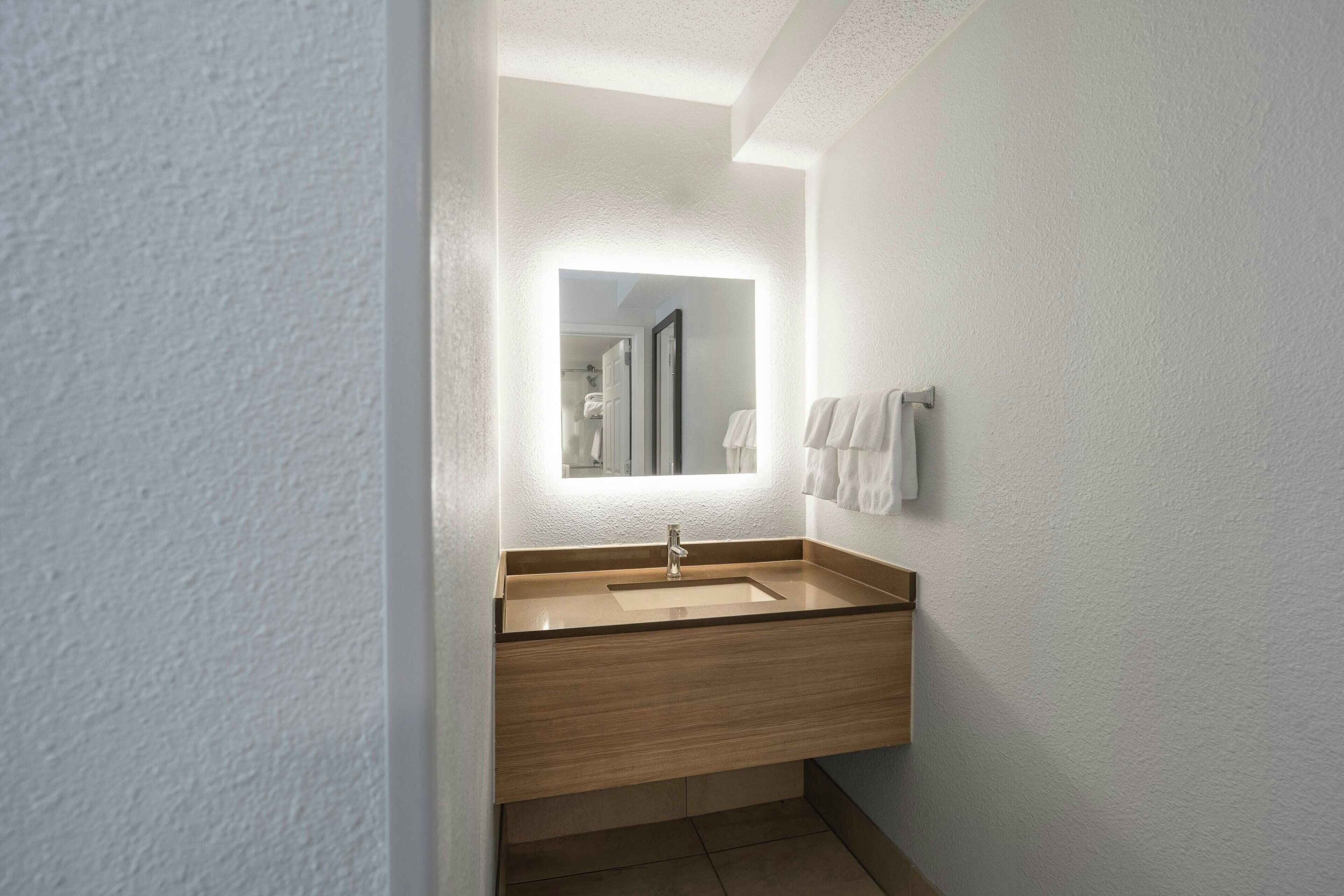 Une salle de bain moderne avec un meuble-lavabo en bois, un évier et un miroir.