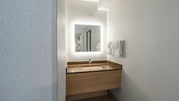 A modern bathroom with a wooden vanity, a sink, and a mirror.