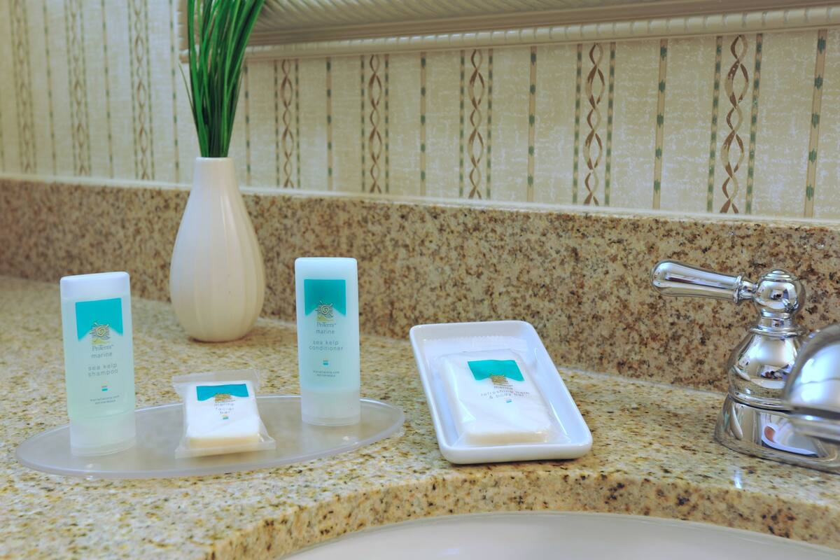 A bathroom counter with toiletries including a shampoo bottle, a conditioner bottle, and a soap dish.