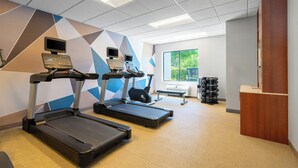 A gym with treadmills, a wall-mounted TV, and a window with a view of greenery. - SpringHill Suites by Marriott Atlanta Kennesaw (Kennesaw)