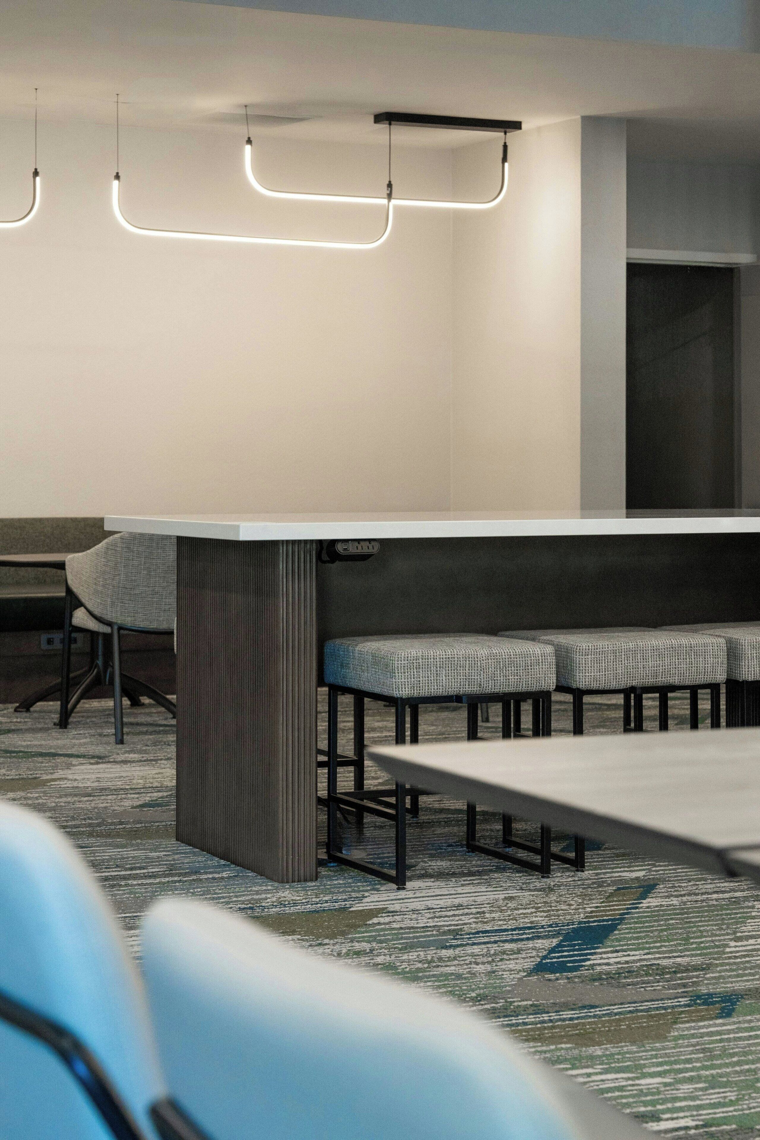 Une salle de conférence avec une longue table, plusieurs chaises et des luminaires suspendus.