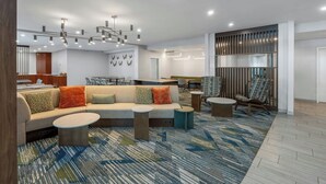 A modern hotel lobby with a sectional sofa, round tables, and a patterned carpet. - SpringHill Suites by Marriott Atlanta Kennesaw (Kennesaw)