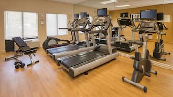 A gym with treadmills, ellipticals, and free weights.