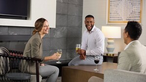 A modern hotel room with a sofa, a small round table, a lamp, and a television. - Staybridge Suites Columbia Baltimore by IHG (Columbia)