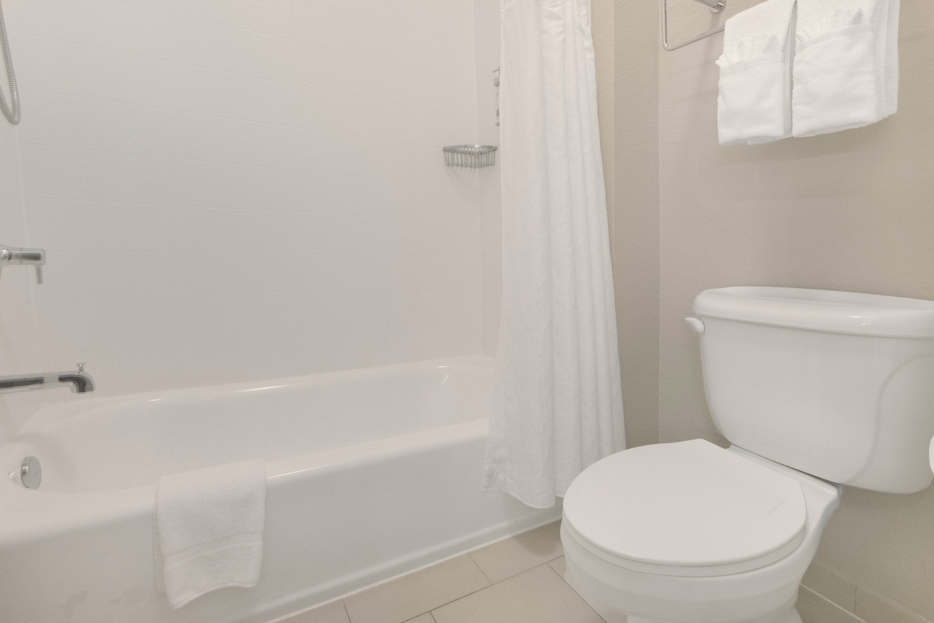 Un baño con bañera, inodoro y cortina de ducha.