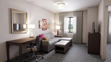Una habitación de hotel con escritorio, sofá, televisión y armario.