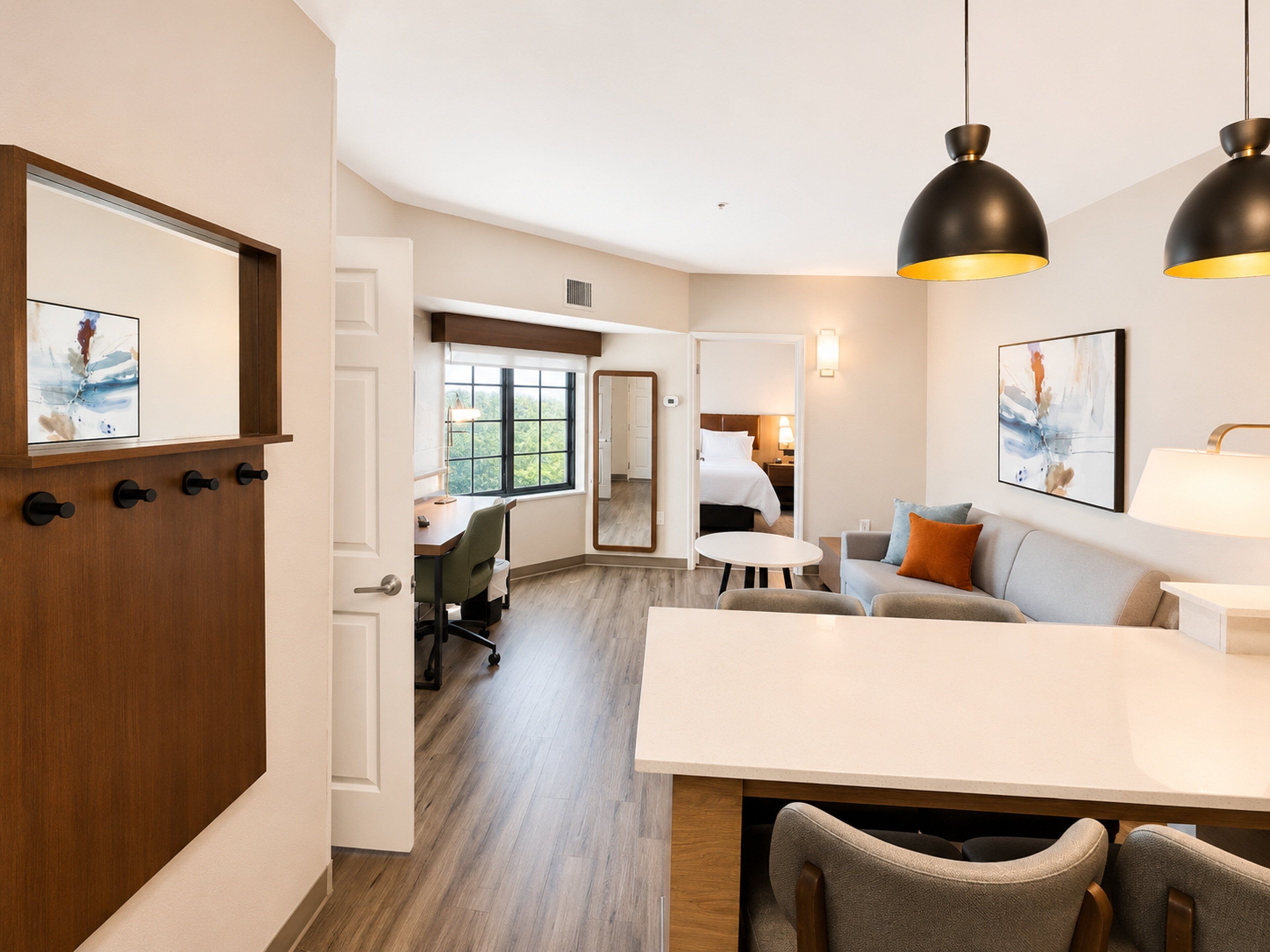 Habitación de hotel con comedor, cama, escritorio y un amplio ventanal.