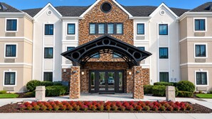 A multi-story building with a stone facade, large windows, and a prominent entrance with a black archway. - Staybridge Suites Columbia Baltimore by IHG (Columbia)