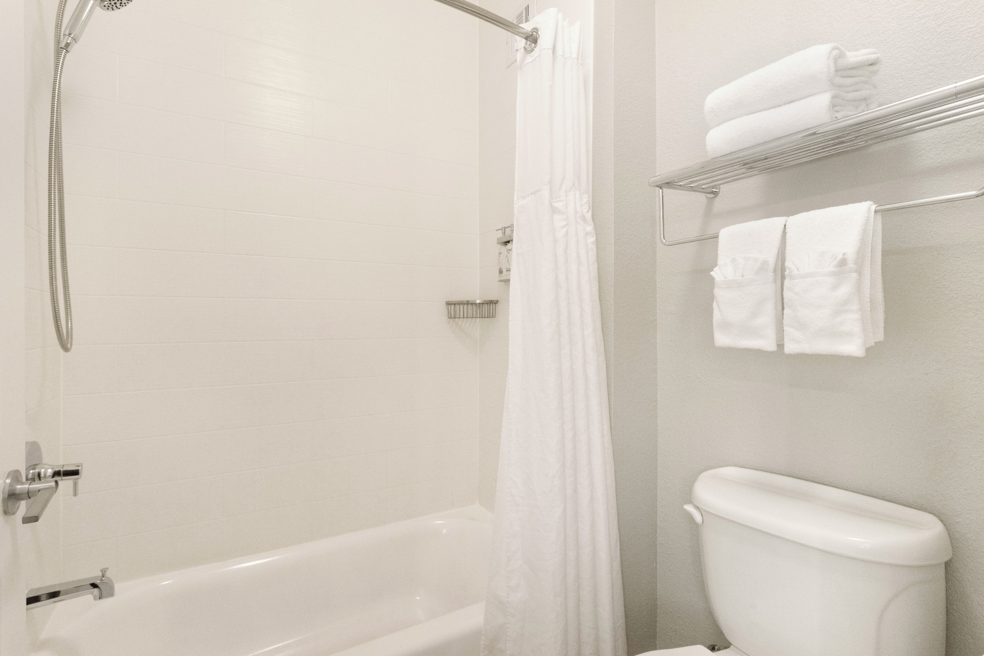 A bathroom with a bathtub, a shower, a toilet, and a towel rack with towels.