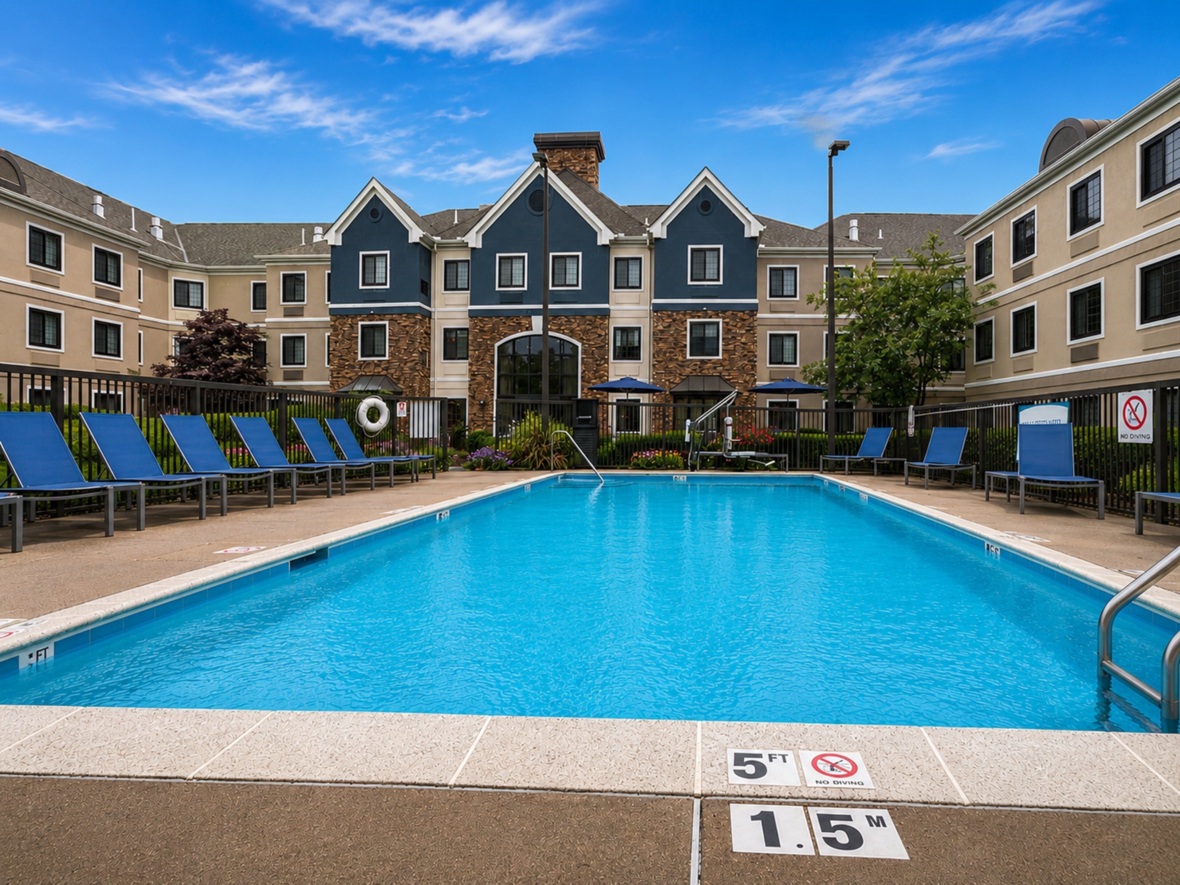 A swimming pool with lounge chairs, a no diving sign, and a 5ft depth marker.