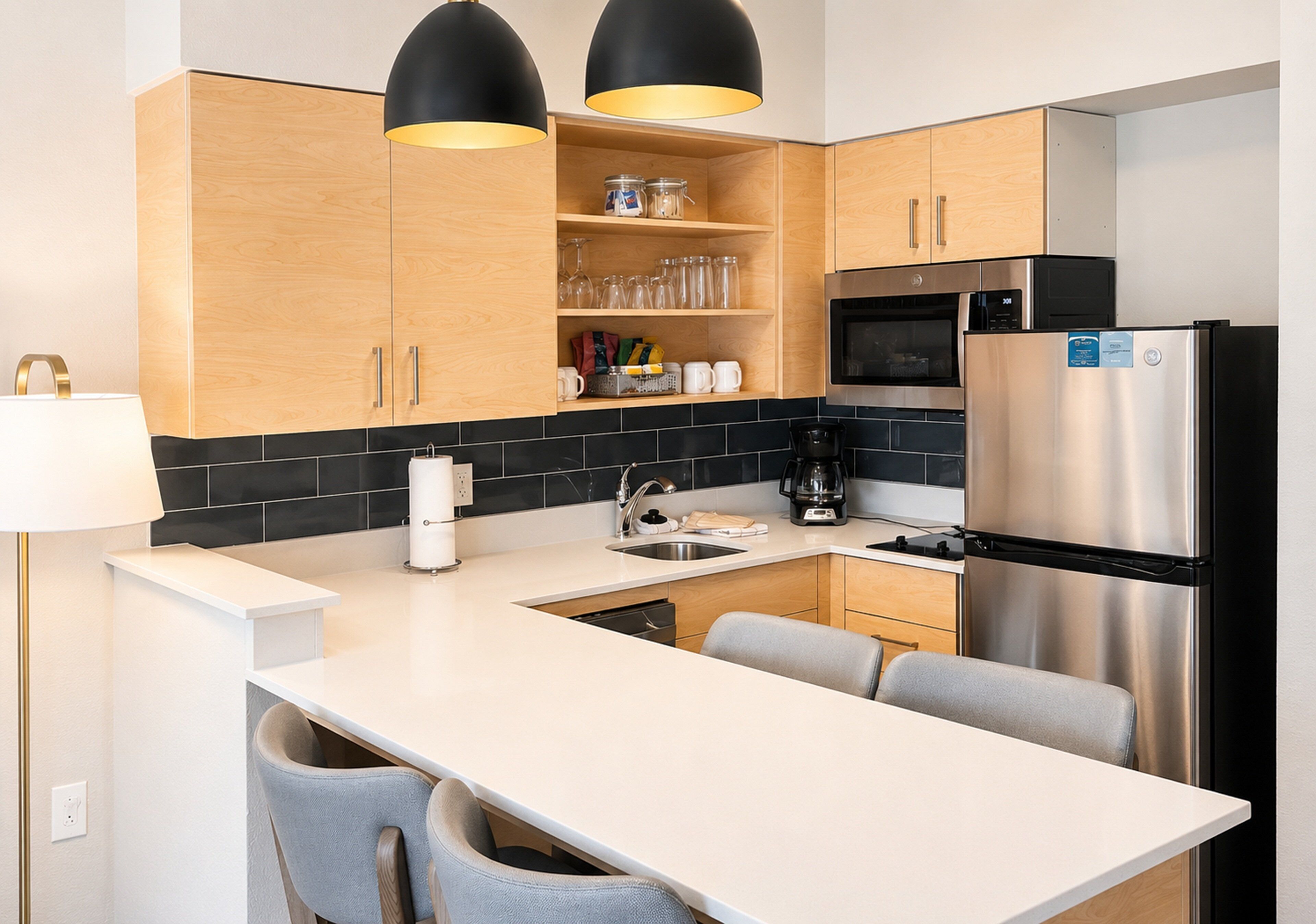 A modern kitchen with wooden cabinets, a stainless steel refrigerator, a built-in oven, and a coffee maker.