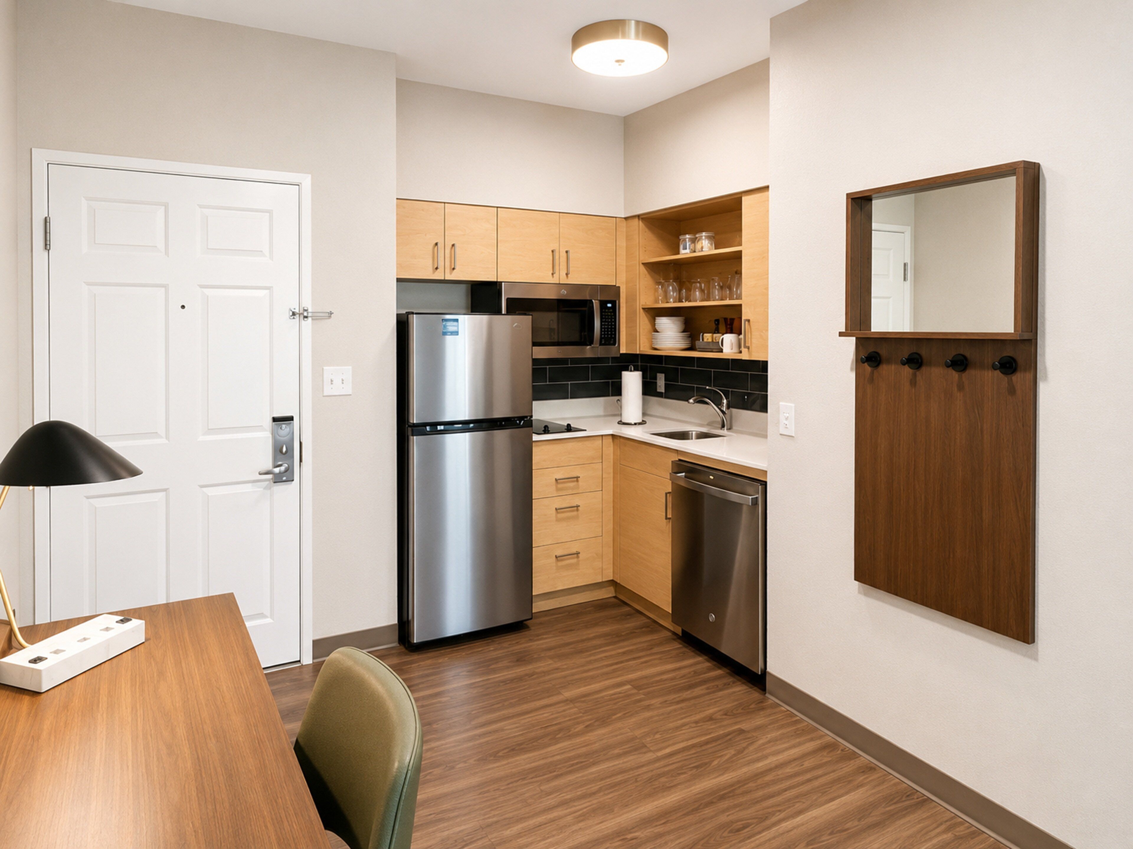 A compact kitchen with a refrigerator, microwave, sink, and wooden cabinets.